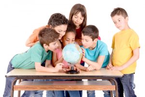 group of kids looking at globe at school isolated in white