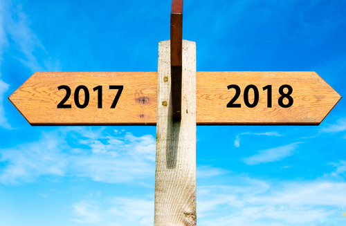 Wooden signpost with two opposite arrows over clear blue sky, year 2017 and 2018 signs, Happy New Year conceptual image