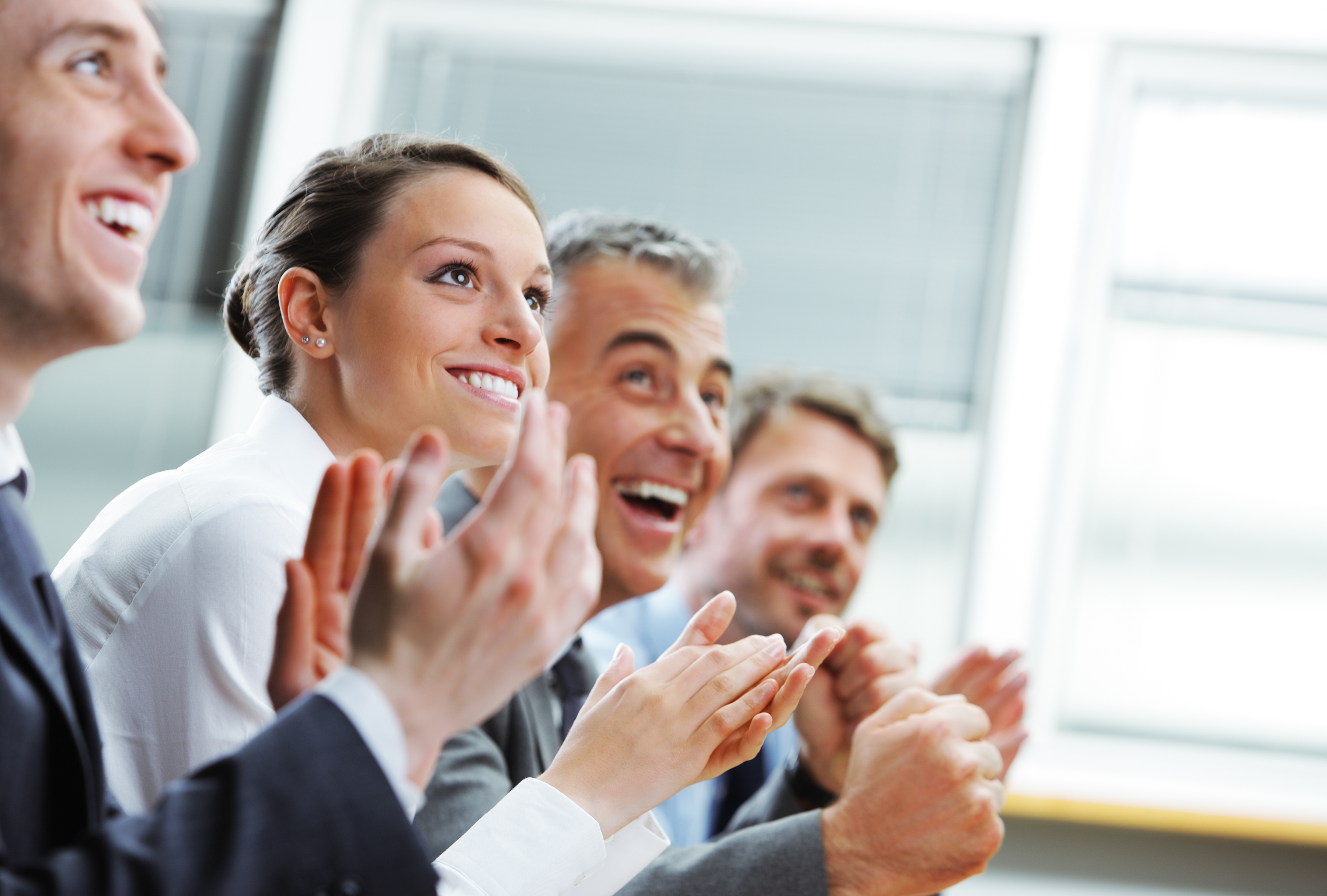 Group of cheerful businesspeople sitting in a row on a presentation and clapping