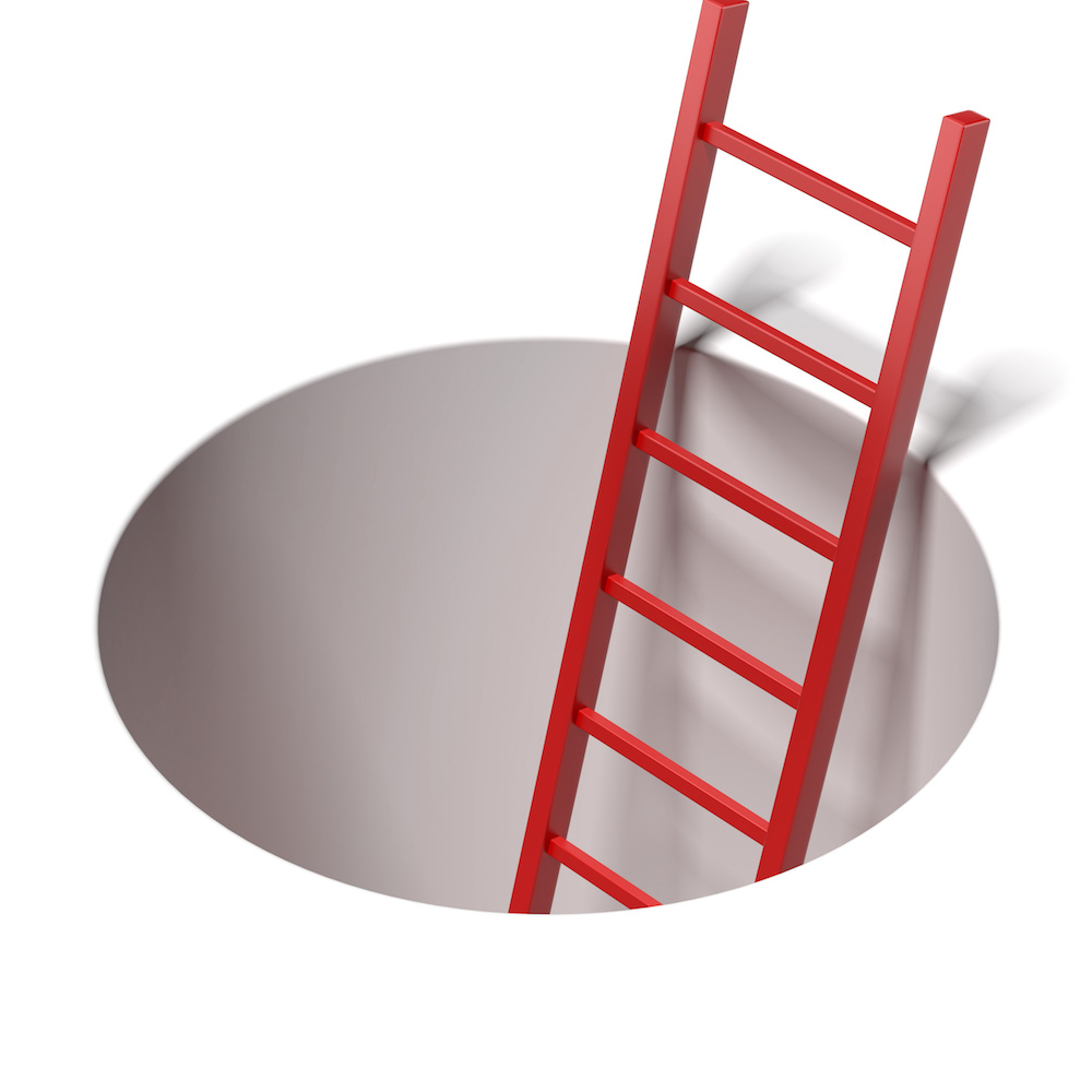 Ladder standing inside hole isolated on a white background